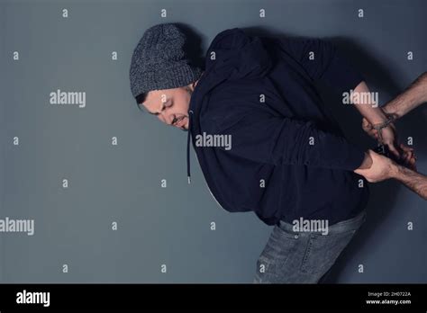 Man Putting Handcuffs On Drug Dealer Against Grey Background Space For Text Stock Photo Alamy