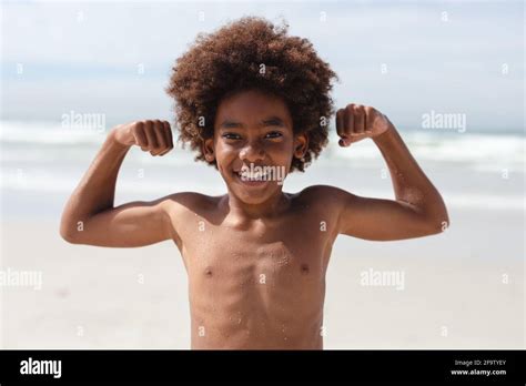 Portrait Of African American Boy Flexing His Biceps At The Beach Stock