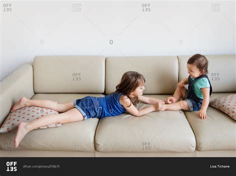 Girl Tickling Feet Of Her Little Sister Stock Photo Offset