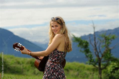 Junge Frau mit Gitarre vor Alpenpanorama lächelt Stock Foto Adobe Stock