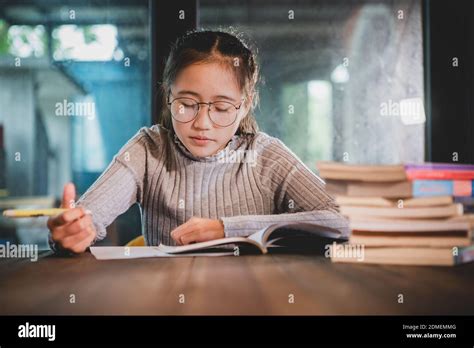 Girl Reading Book On Table At Home Stock Photo Alamy