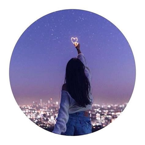 A Woman Holding Up A Heart Shaped Object In Front Of A Cityscape At Night