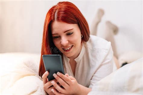 Smiling Young Woman Chatting On Her Cell Phone Lying On Her Bedroom Bed Stock Image Image