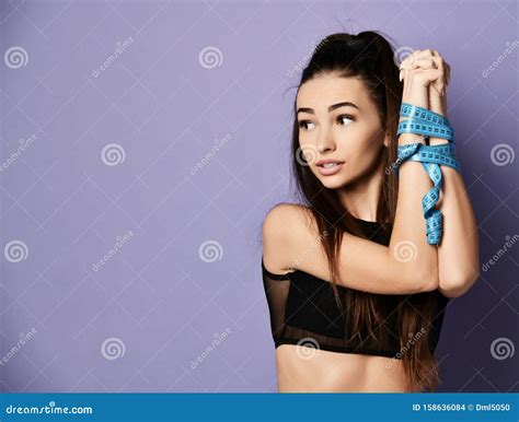 diet weight loss concept pretty sport woman hold hands tied up with tape measure on purple