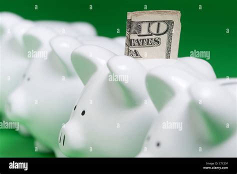 Piggy Banks Lined Up In A Row With One Piggy Bank With A Ten Dollar