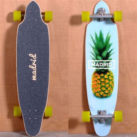 two skateboards with pineapples on them against a wall one is blue and the other has yellow wheels