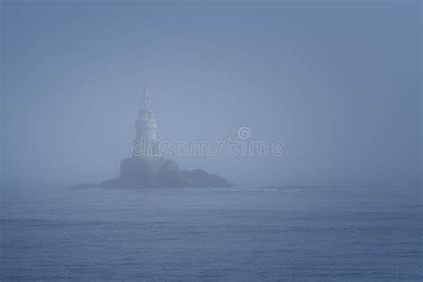 Lighthouse Along Rocky Coastline On Foggy Morning Stock Photo Image