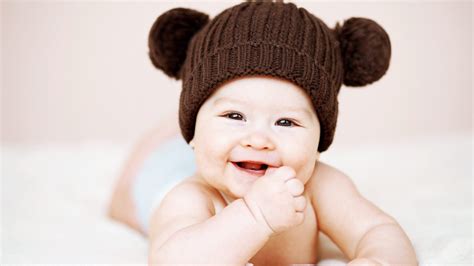 Cute Smiley Baby Is Wearing Brown Knitted Woolen Cap Having Hand On