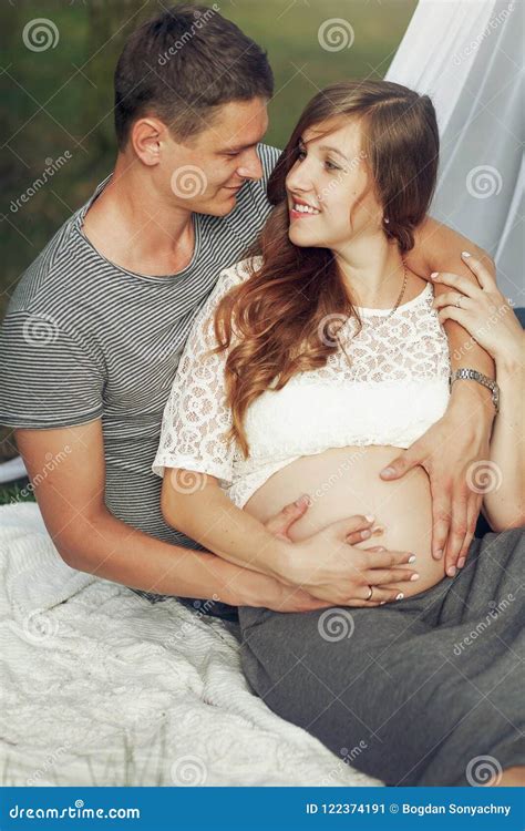 Handsome Husband Hugging Pregnant Wife From Behind While Sitting In Summer Park Tender Moments