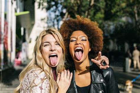 Two Young Women Sticking Out Tongue And Looking At Camera By Victor Torres
