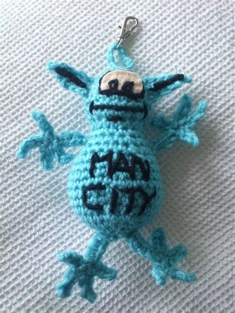 A Blue Crocheted Keychain With The Word Happy On Its Face