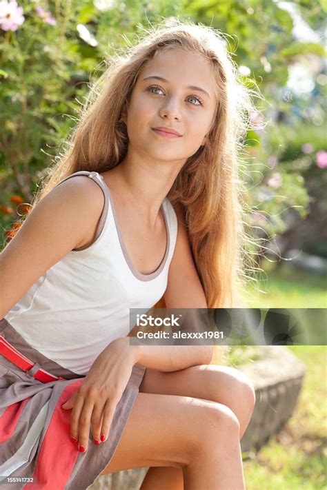 Beautiful Female Teenager Sitting Outdoors On Curbs Posing Looking Away