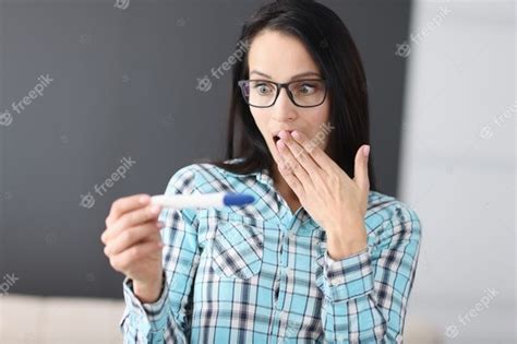 premium photo surprised woman with glasses looking at pregnancy test at home