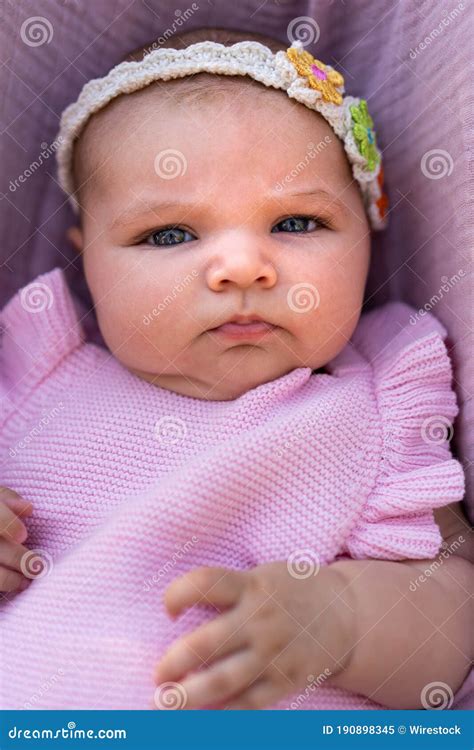 Newborn Baby Girl Wearing Pink Knitted Clothes And A Floral Head