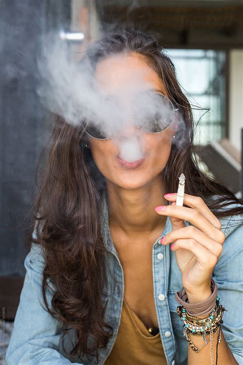 beautiful tanned girl blowing cigarette smoke into the camera by jovo jovanovic urban smoke