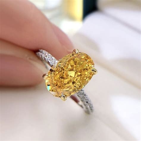 A Fancy Yellow Diamond Ring Being Held By Someone S Hand