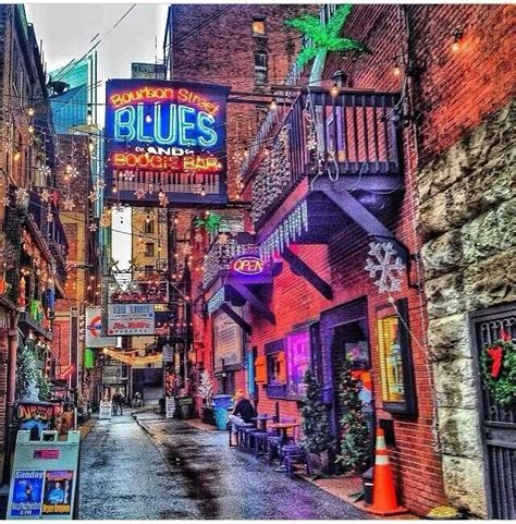 An Alleyway With Signs And Lights On The Buildings In The City At