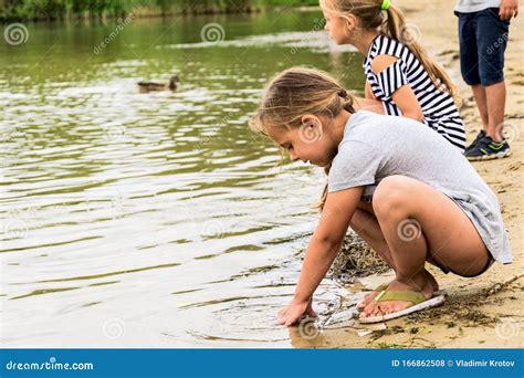 Two Little Girls Are Sitting On The Lake Stock Photo Image Of Child