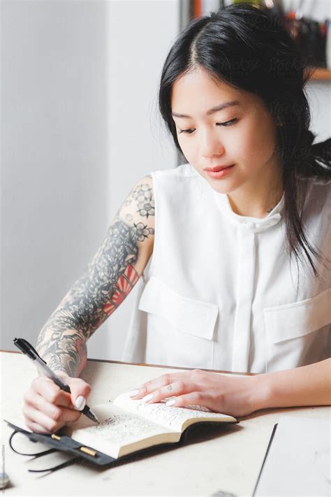 Young Asian Woman Writing Ideas On Her Notebook By Giorgio Magini