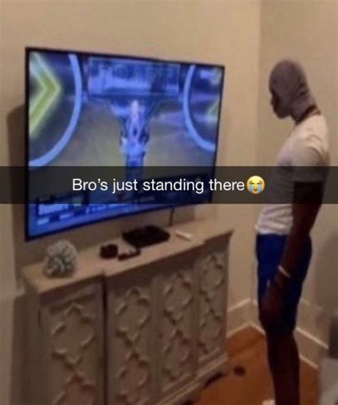 a man standing in front of a tv with the caption bro s just standing there