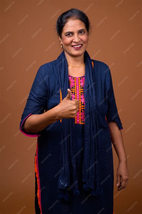 premium photo mature beautiful indian woman against brown wall