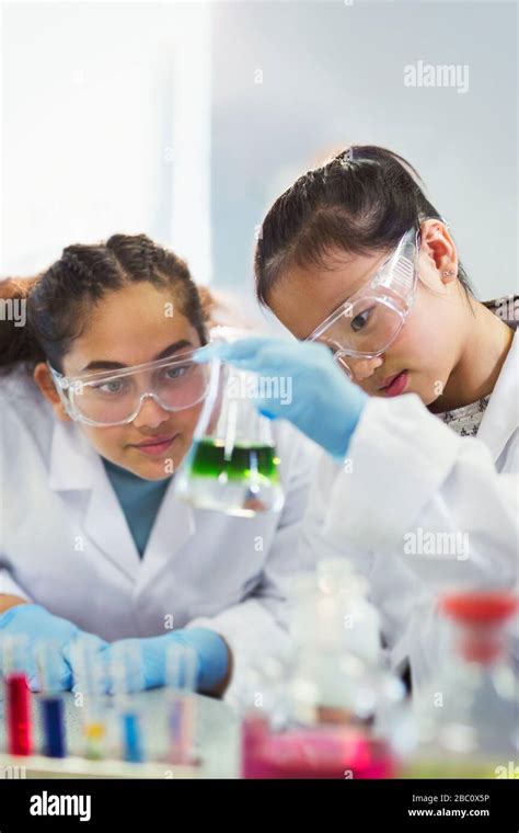 Girl Students Examining Liquid In Beaker Conducting Scientific
