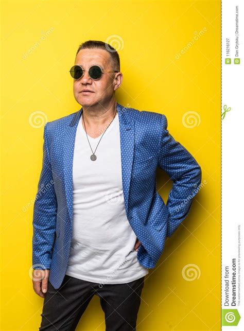 elegant smiling mature man portrait wearing a pair of sunglasses isolated on yellow background