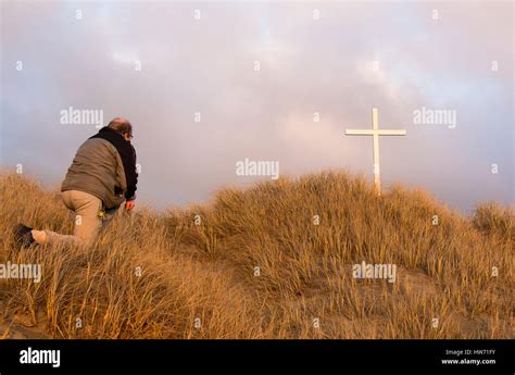 Man Kneeling Before A White Cross On A Hill Stock Photo Alamy
