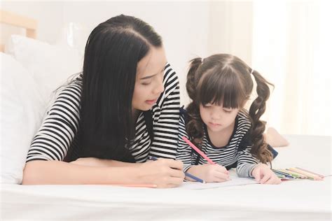 Feliz Madre Asiática Enseñando A Su Linda Hija A Estudiar En La Sala De