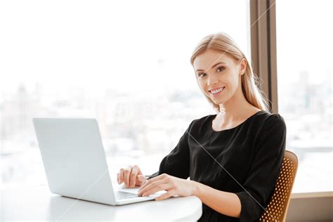 Happy Young Woman Working In Office With Laptop Typing And Looking At