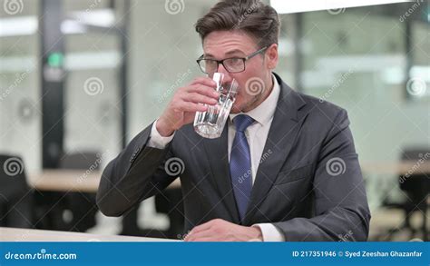 Portrait Of Thirsty Middle Aged Businessman Drinking Water Stock Photo