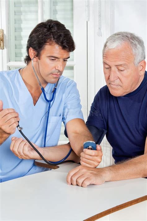 Male Nurse Checking Blood Pressure Of A Senior Man Stock Photo Image