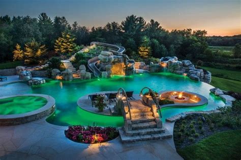 An Aerial View Of A Pool At Night With Lights On The Water And Trees In