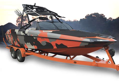 An Orange And Black Boat On Trailer With Trees In The Backgrouds Behind It