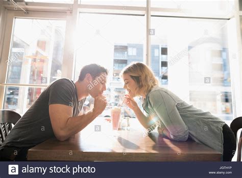 Young Couple Sharing Milkshake At Sunny Diner Table Stock Photo Alamy
