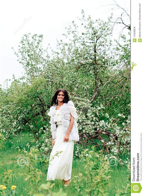 Beautiful Young Girl In White Dress In Spring Blossoming Apple Orchards