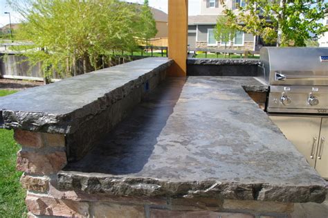 Black polished concrete countertop on an outdoor kitchen featuring black wicker bar stools on rustic plank floors. Rustic Outdoor Concrete Countertop Kitchen - Rustic ...