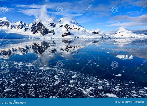 Antarctic Landscape With Snow On Mountains Reflecting In Blue Water