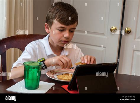 Young Boy Nine Years Old Watching His Ipad While Eating Breakfastmr
