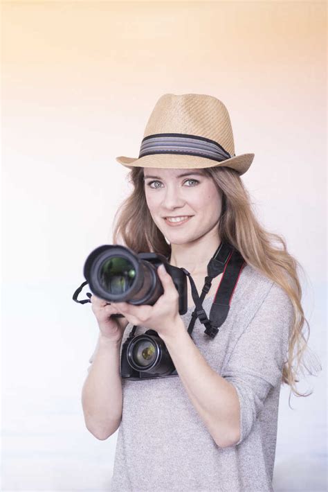 Portrait Of Smiling Young Woman Comparing Two Different Cameras Stock Photo