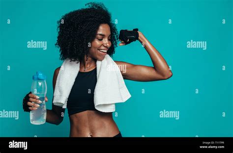 Young Fitness Woman Flexing Muscles And Smiling Against Blue Background
