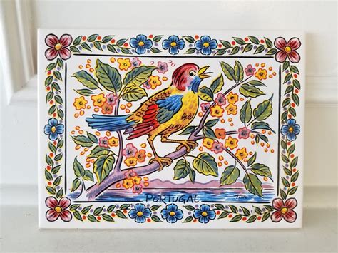 A Colorful Bird Painted On The Side Of A White Tile With Blue Yellow