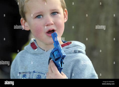 A Young Boy Holds A Toy Gun Near To His Mouth Stock Photo Alamy