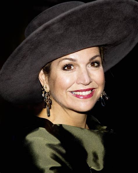 A Woman Wearing A Black Hat And Green Dress Smiling At The Camera While