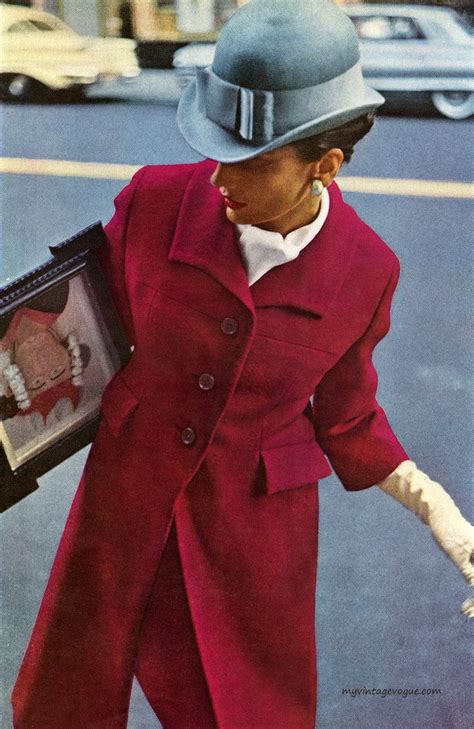 A Woman In A Red Coat And Hat Walking Down The Street