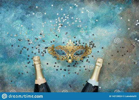 Two Champagne Bottles Golden Carnival Mask And Confetti Stars On Blue
