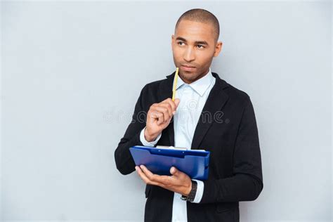 Thoughtful African Young Man Writing On Clipboard Stock Image Image