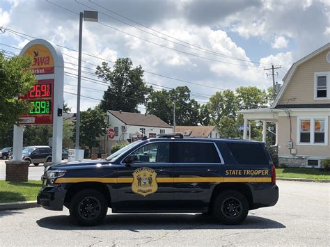 A State Trooper Vehicle Parked In Front Of A Gas Station Sign With The