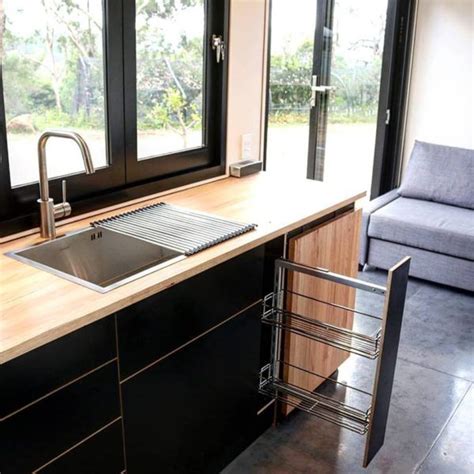 A Kitchen With Black Cabinets And Stainless Steel Sink In Front Of A