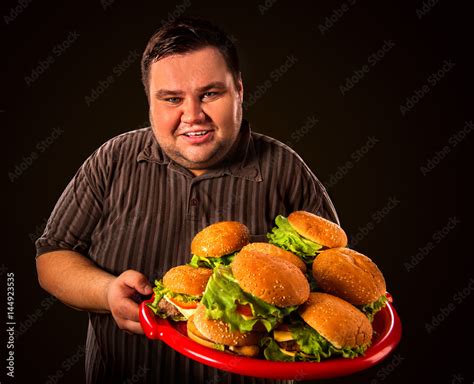 Fat Man Eating Fast Food Hamberger And Carries Treat For Friends On Tray Breakfast For